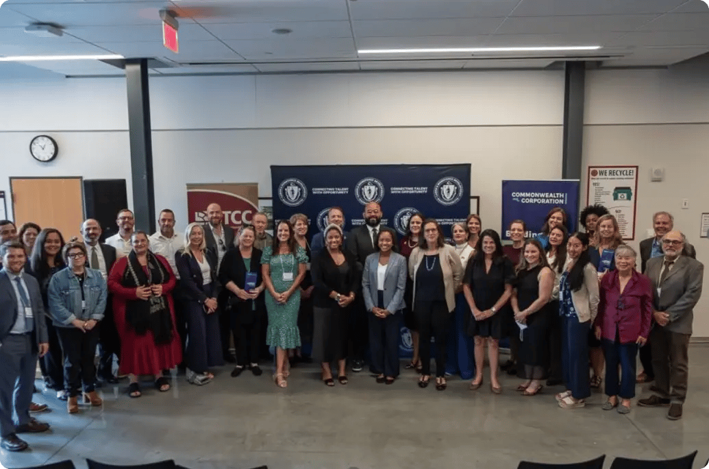 A group of individuals gathers for a photo at an event, with banners in the background promoting talent and opportunity.